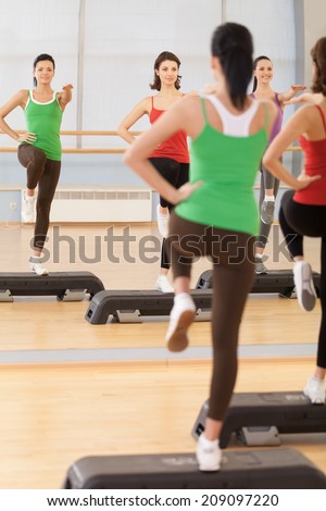 Full length portrait of instructor with fitness class. young girls performing step aerobics exercise in gym