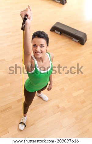 top view of young pretty fit woman exercising. woman with elastic fitness band looking up