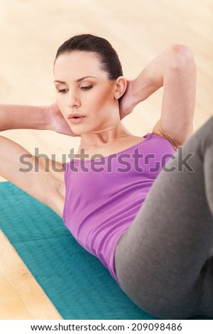 slim mid aged woman do her fitness exercises. pretty girl working out on floor and holding hands behind