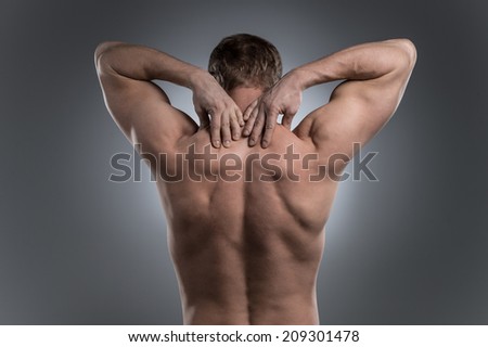 Close-up of young shirtless man with neck pain. young man standing on grey white background