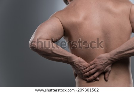 back of young shirtless man with back pain. young man standing on grey white background