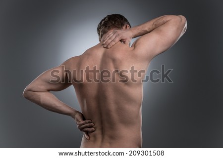 back view of young shirtless man with neck pain. young man standing on grey white background