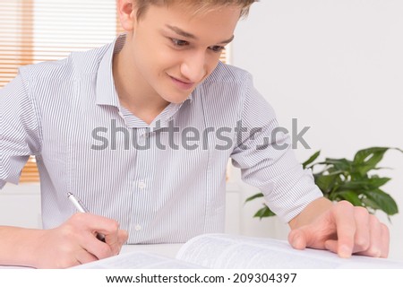 university student writing paper work. young man preparing to exams at home