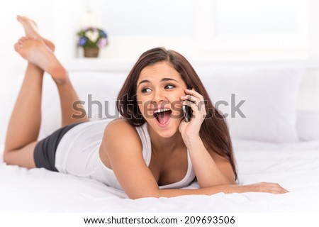 Beutiful happy woman talking at mobile phone. Undressed young girl lying in bed and talking