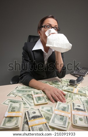 Closeup of businesswoman sitting at table and holding bag to mouth. tired and sick woman sitting at the table covered with money