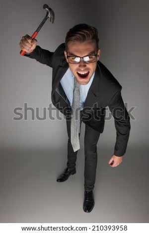 Angry businessman about to hammer on grey background. angry and fierce looking mature guy with hammer
