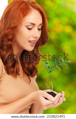 Profile of girl holding little plant in her hands. Woman\'s hands holding soil with plant and smiling