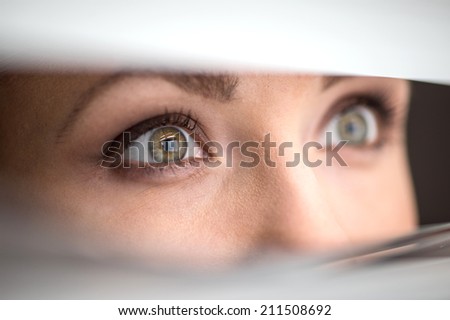 beautiful woman peeking through jalousie. Woman eyes peering through blinds