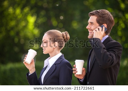 Business people drinking coffee outside. handsome guy talking on mobile and smiling