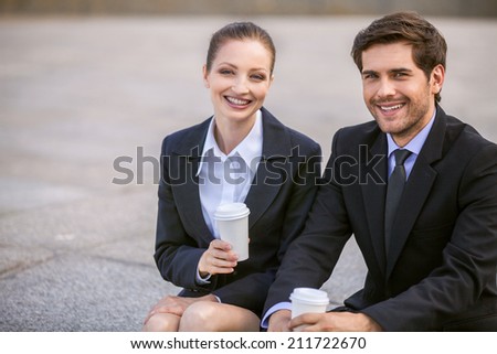 Business people drinking coffee outside. Business partners smiling while on stairs