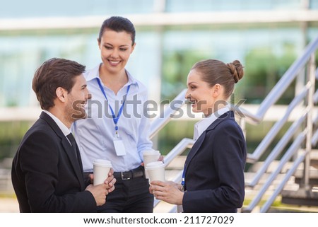 Three smiling business people standing on stairs. portrait of young business man looking at woman