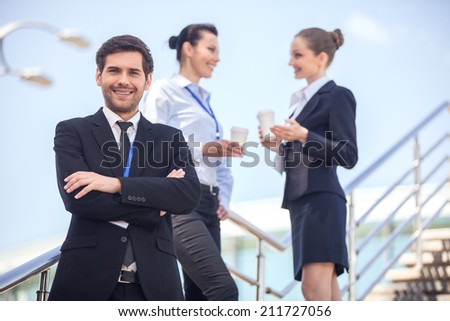 Three smiling business people standing on stairs. closeup of young business man looking at camera