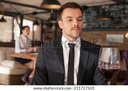 Stylish young man sitting in bar. Handsome man drinking glass of red wine in bar