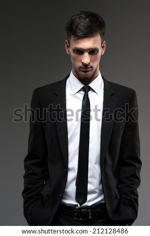 Handsome young man on grey background. front view of man in unbuttoned suit looking into camera