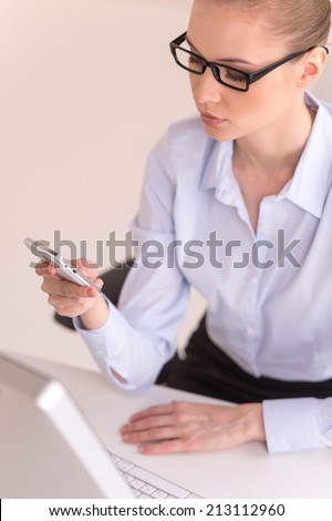 blond businesswoman texting on phone in office. closeup of young office worker using cell phone