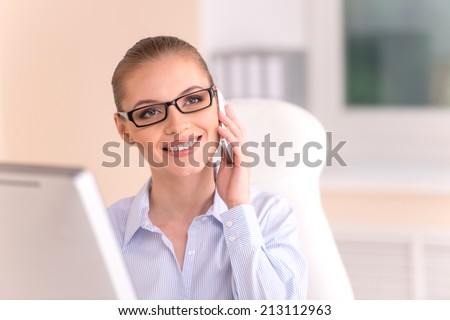 blond businesswoman talking on phone in office. closeup of young office worker using cell phone