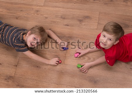 Two friends playing on floor at home. top view of boys playing with toy cars and looking up