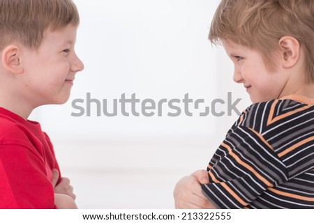 Two young boys standing face to face. Two teenage boys looking at each other isolated on white.