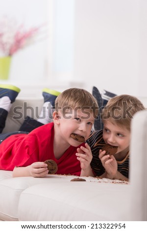 two cute boys lying on couch. two friends eating cookies and resting