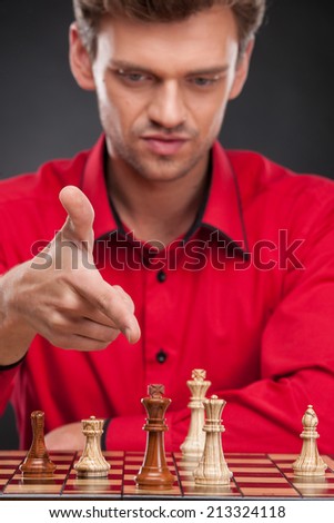 Young casual man sitting over chess. man pointing at chess pieces on board