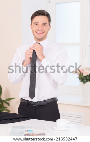 Close-up of businessman adjusting neck tie. waist up of handsome guy putting on neck tie