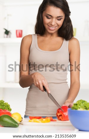 beautiful young woman with salad, isolated on white. Woman making salad in kitchen using knife