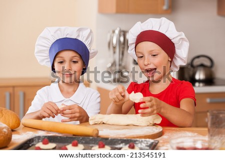 little children making cakes and talking. two little boys having fun at kitchen table
