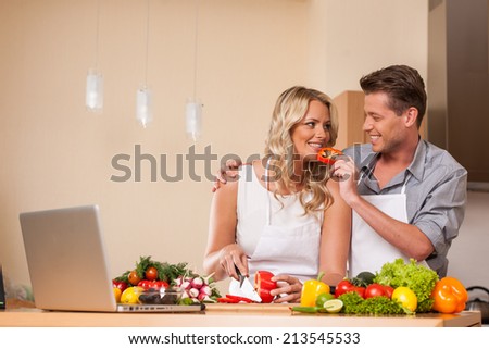 handsome man feeding woman at kitchen. man and woman preparing food at kitchen counter