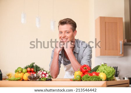 handsome man leaning on chopping board. guy preparing food at kitchen counter