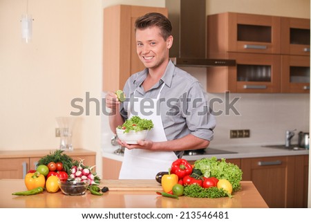 handsome man squeezing lime for fresh salad. guy preparing healthy food at kitchen