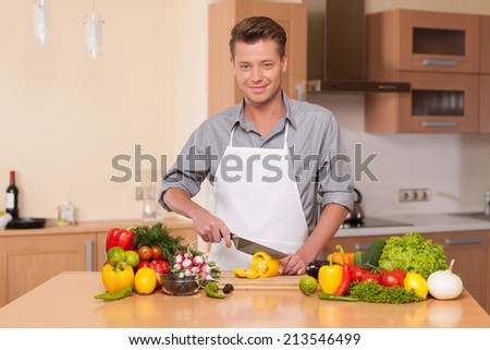 Caucasian man cutting pepper on chopping board. guy preparing food at kitchen counter