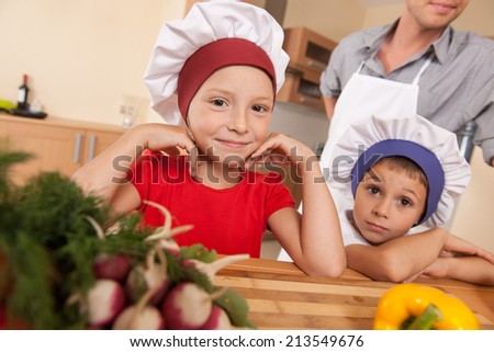 Portrait of parents and two children making food. sister and brother leaning on table and smiling