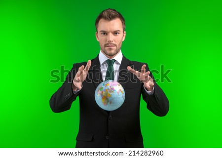 Young businessman keeps world in his hands. Business man protecting Earth on green background
