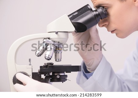 male scientist working in ab with microscope. clinician studying chemical elements in laboratory