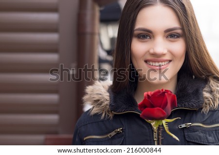 Pretty young brunette woman and red rose. Portrait of beautiful woman with red rose