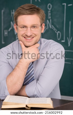 confident young teacher and classic chalkboard background. fine image of young caucasian teacher at school
