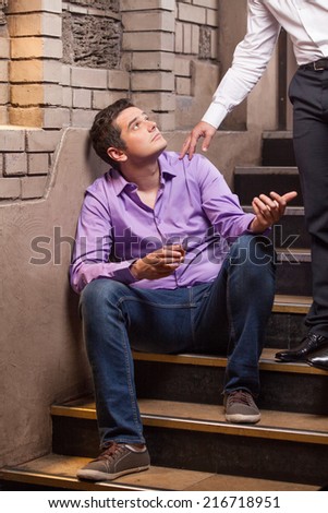 Handsome young man talking to man sitting on stairs. closeup of guy drinking whisky and thinking