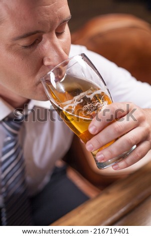closeup portrait of man drinking beer. man holding glass of light beer