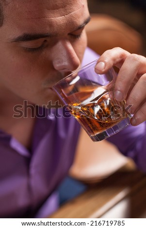closeup of young man drinking alcohol drinks. man sitting in bar and resting after work