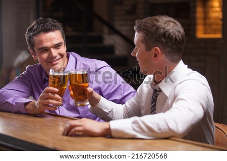 two young man talking at counter. two friends sitting in bar and drinking beer