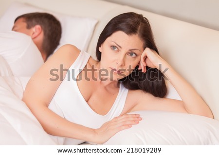 unhappy woman lying in bed stressed. couple having problem while man sleeping