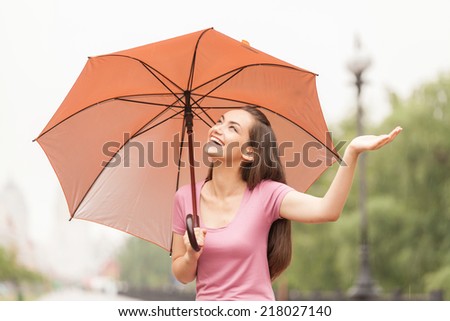 beautiful young girl with orange umbrella. young woman standing outside and looking up
