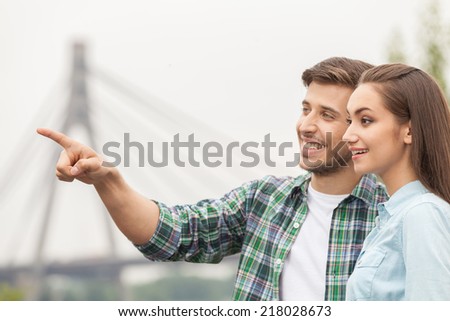 handsome man showing pretty girl. woman looking at man pointing far and smiling