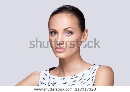 closeup on elegant woman in fashionable stylish white dress posing in studio. Fashion studio shot of beautiful woman with makeup