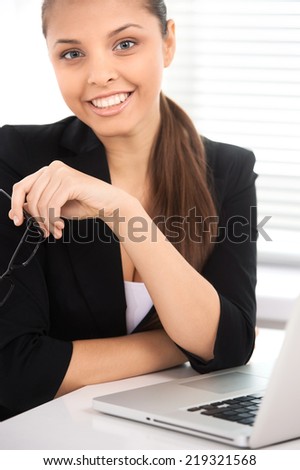 portrait of businesswoman sitting at desk with laptop. Beautiful smiling woman looking into camera isolated on white