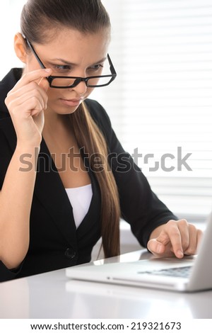 Beautiful woman sits at table and working on laptop. pretty brunette using computer and looking at screen