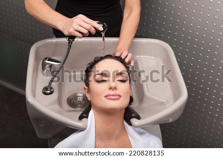 Beautiful woman having her shampoo washed at hairdresser\'s. Hairdresser washing woman head in barber shop