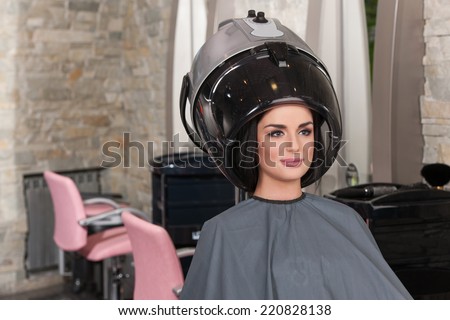women at hairdresser while drying under hairdryer. Portrait of woman under hairdressing machine in parlor