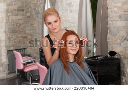 Choice of tone of hair in hair salon. Female redhead client and blond hairdresser choosing shades of colour in salon