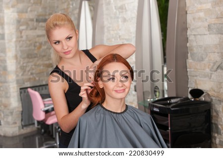 Happy redhead woman getting new haircut. Beautiful blond hairdresser selecting new haircut for female customer at parlor